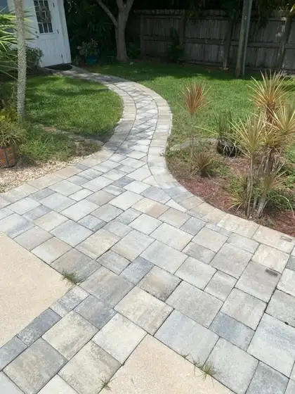 A cleaned paver walkway curving through a South Florida side yard